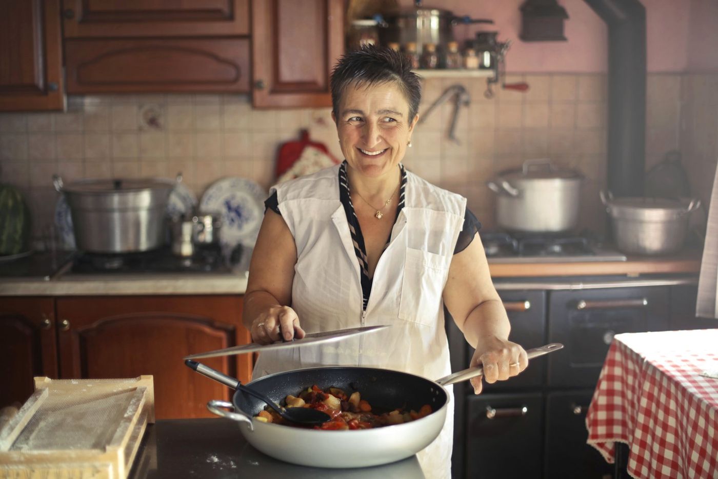Mutfakta gülümseyerek yemek pişiren bir kadın